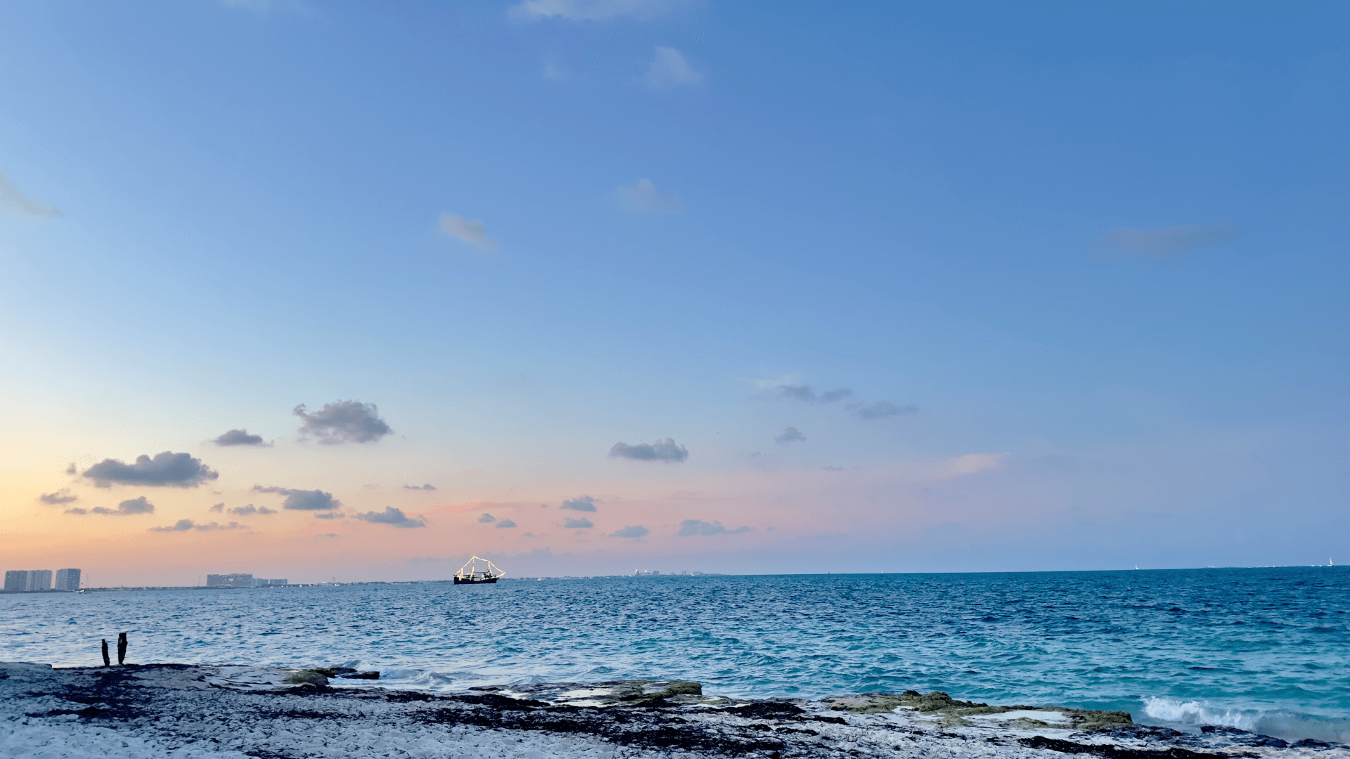 Fondo de playa y mar Caribe con un barco de tours en Cancun